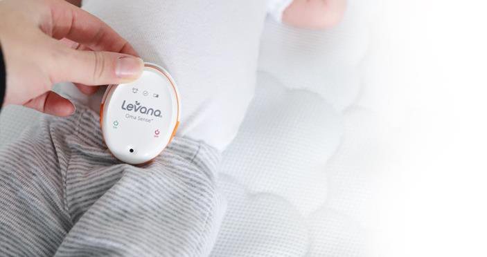 Oma Sense wearable breathing monitor clipped to an infant's clothing